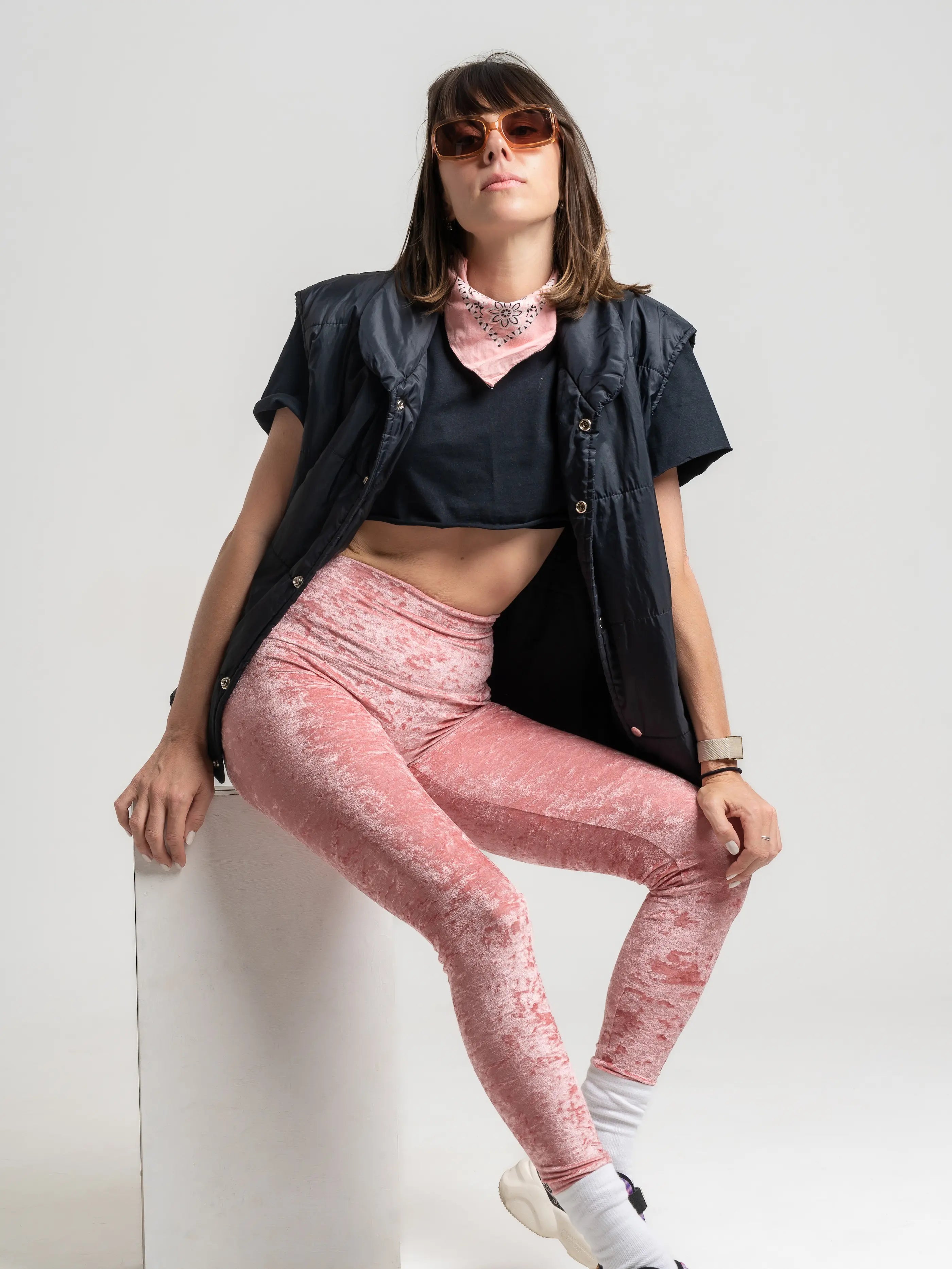 Modèle en legging velours rose stylisé avec une doudoune sans manche noir pour un look sportif.