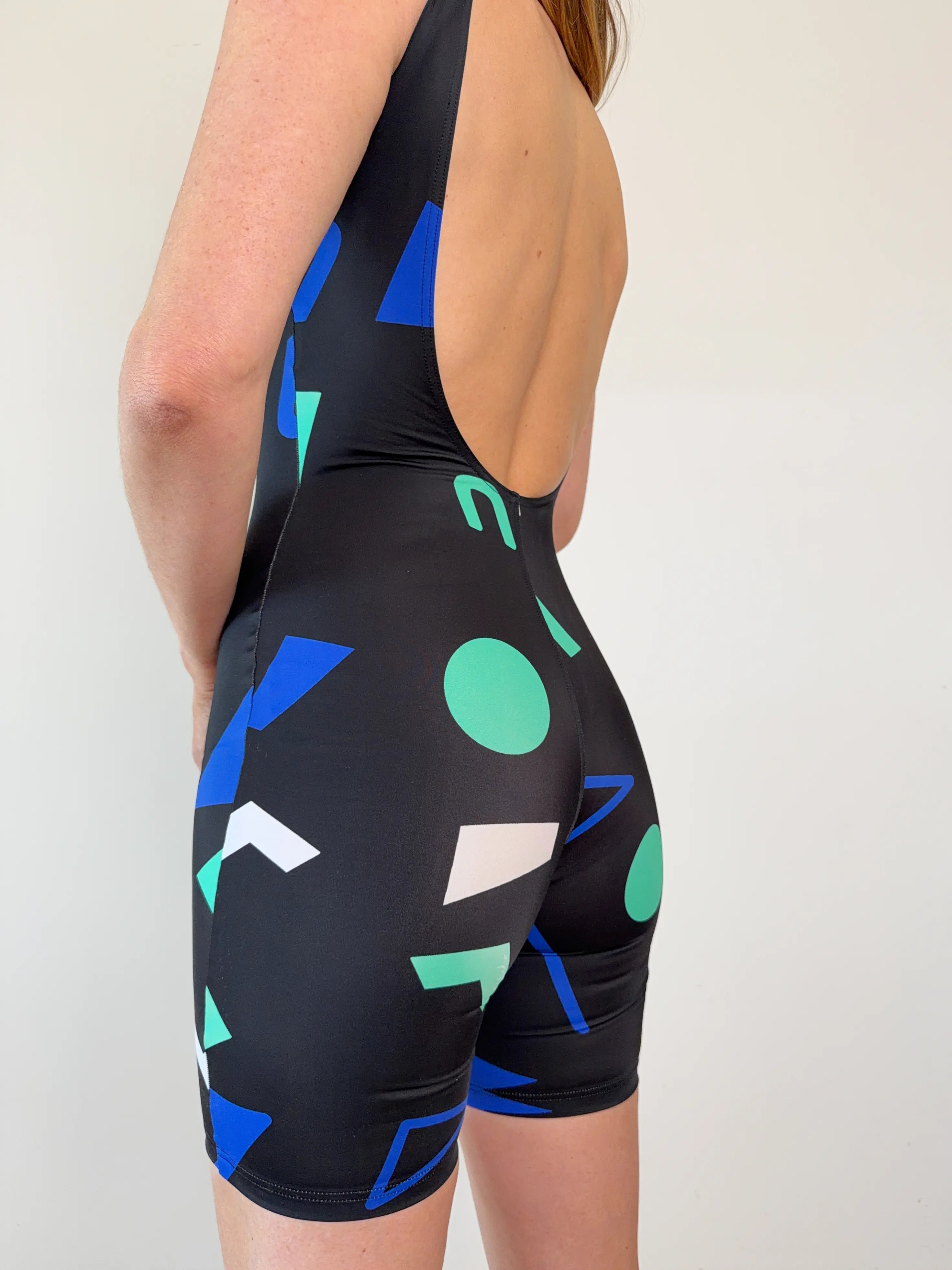 Zoom sur le dos nu de la combinaison short en lycra avec des motif coloré signé UJO